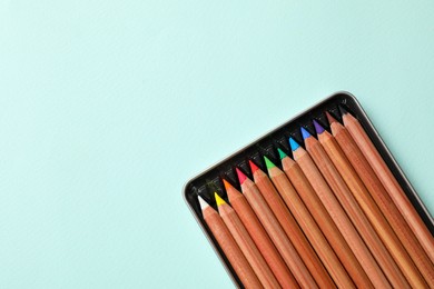 Box with many colorful pastel pencils on turquoise background, top view and space for text. Drawing supplies