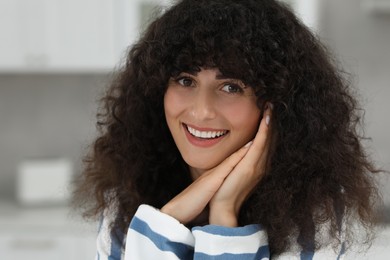 Portrait of beautiful woman with curly hair on blurred background. Attractive lady smiling and looking into camera