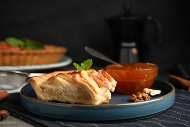 Photo of Slice of delicious apple pie and jam on table