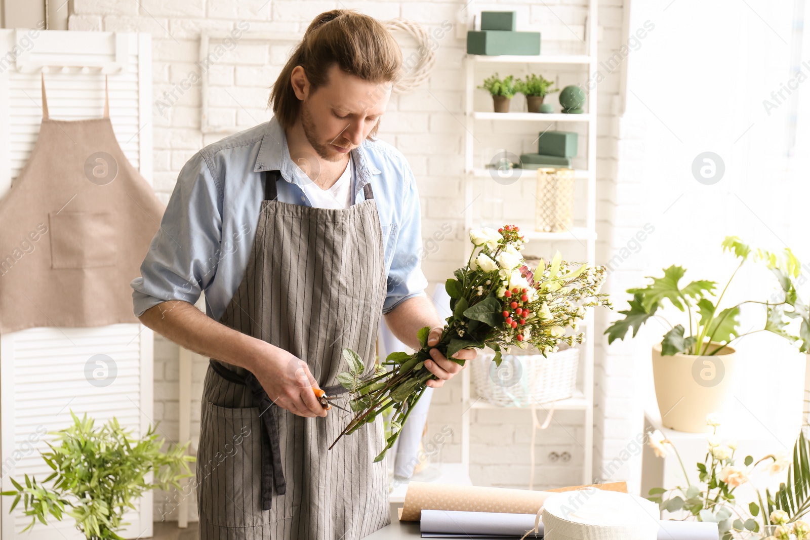 Photo of Male florist pruning stems at workplace