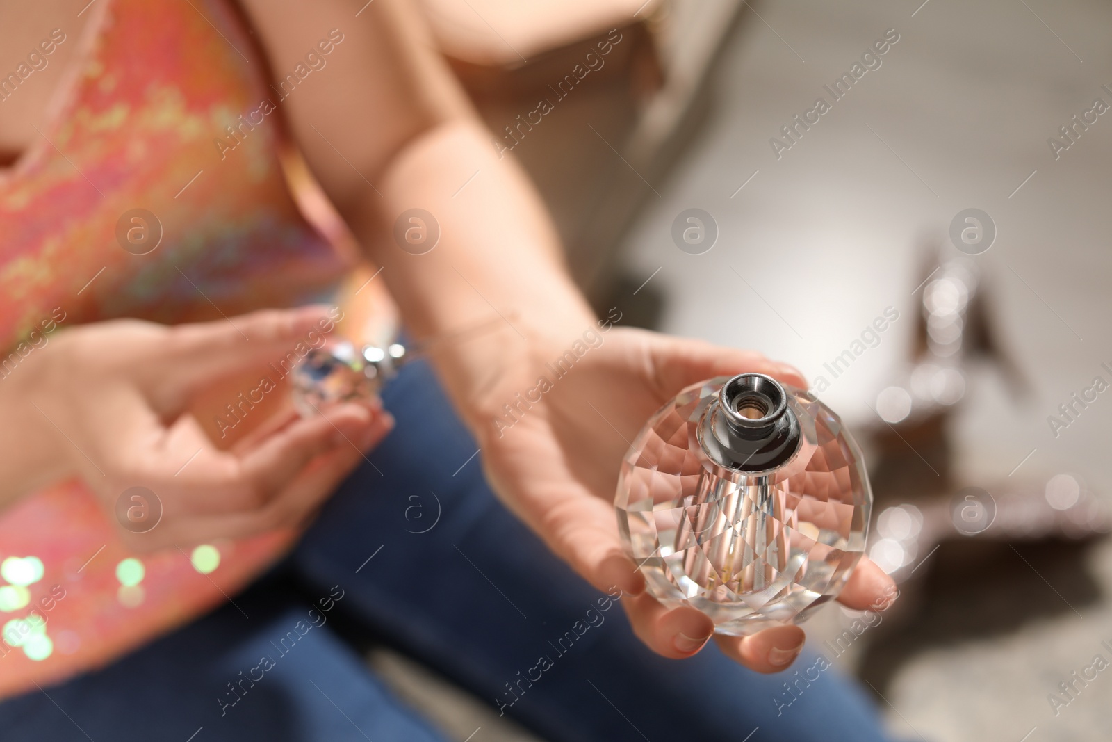 Photo of Young woman applying perfume on wrist against blurred background, closeup