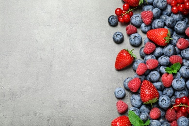 Photo of Different fresh berries on grey background, flat lay. Space for text