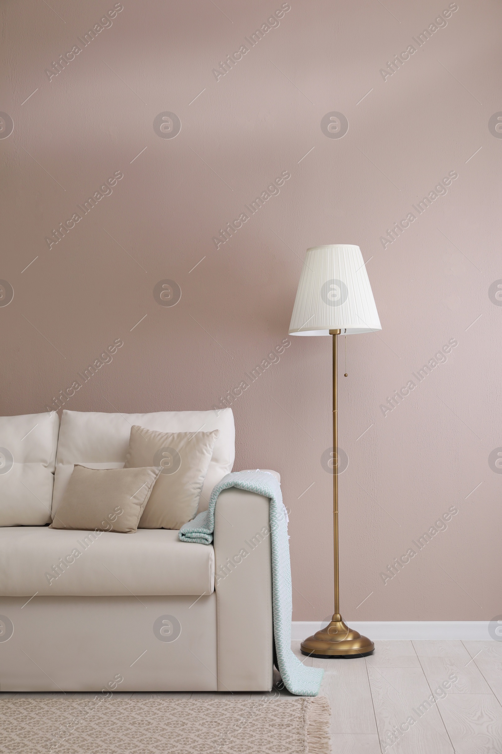 Photo of Stylish room living interior with comfortable sofa and lamp near beige wall