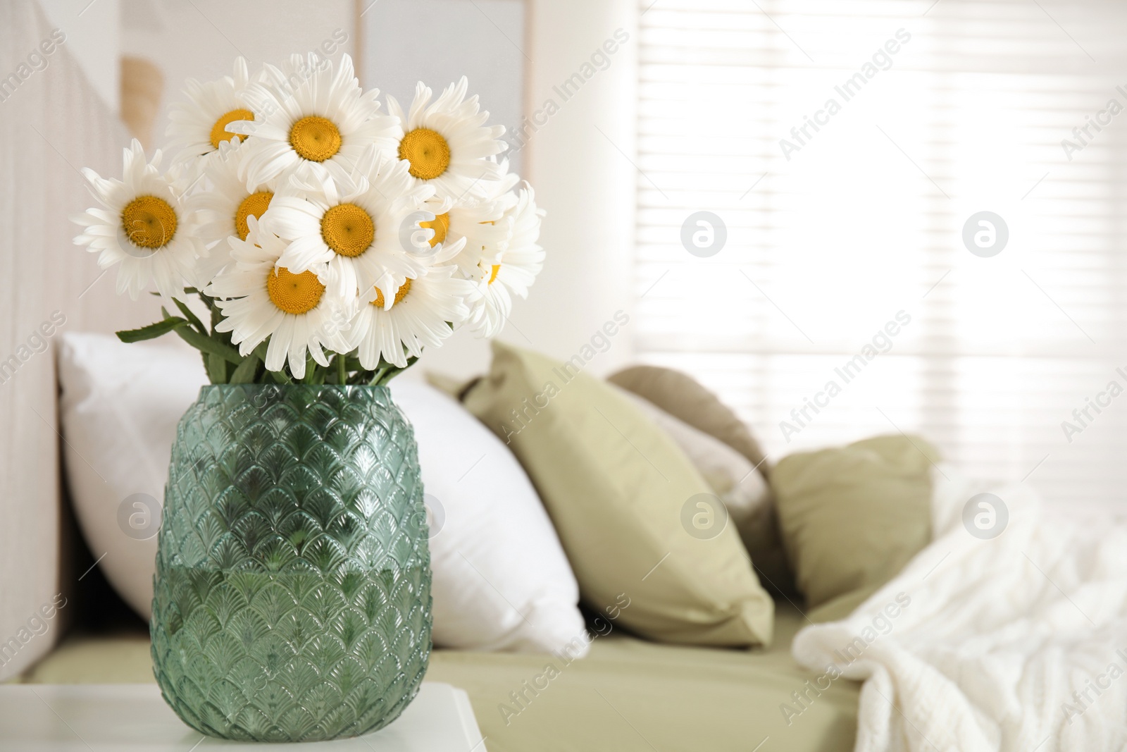 Photo of Bouquet of beautiful daisy flowers on nightstand in bedroom, space for text
