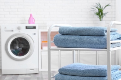 Photo of Folded clean terry towels on shelving unit in laundry room, space for text