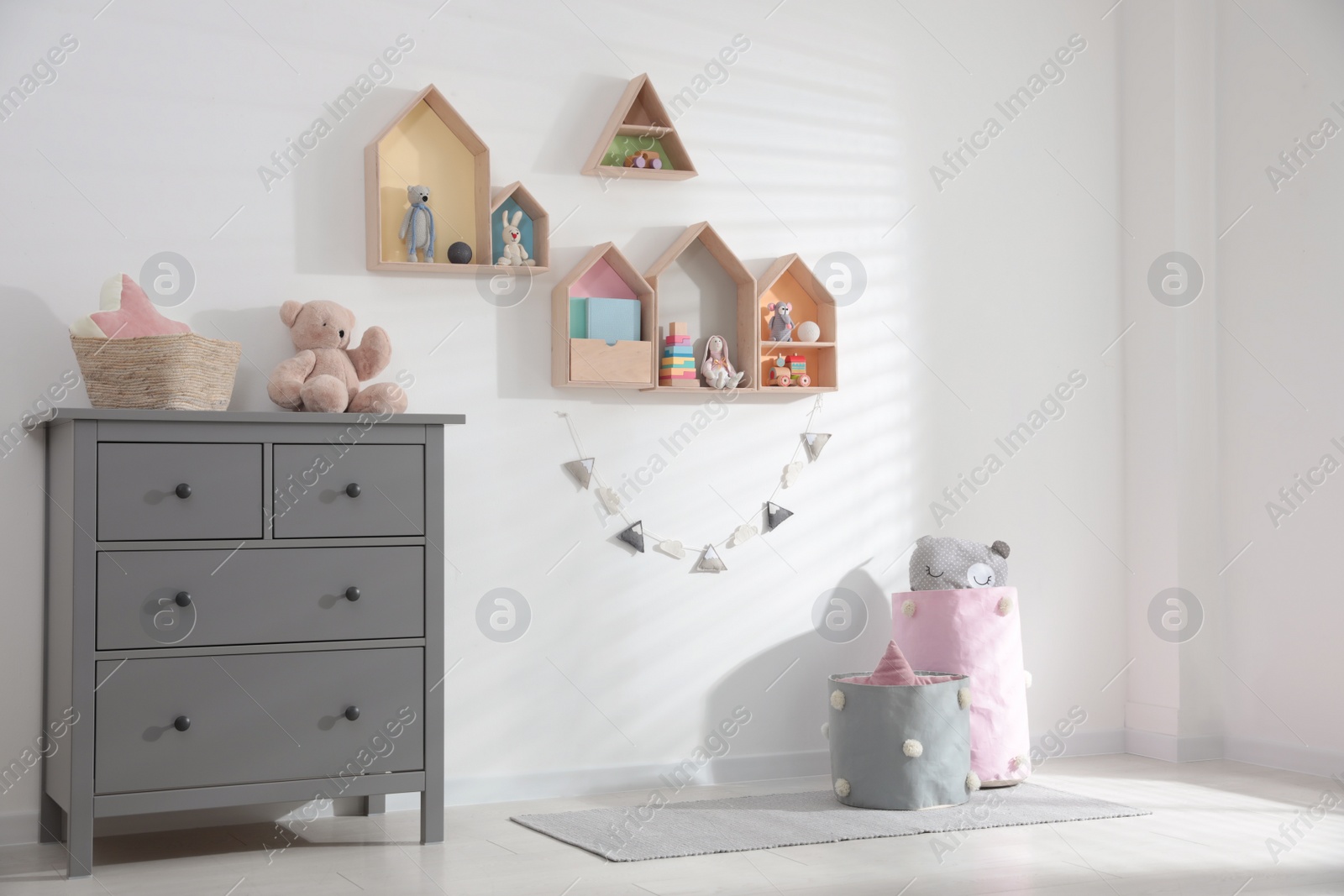 Photo of Cute children's room with house shaped shelves and chest of drawers. Interior design