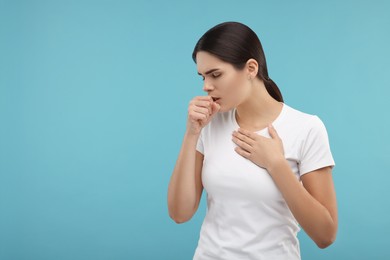 Photo of Woman coughing on light blue background, space for text. Cold symptoms