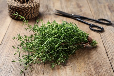 Bunch of aromatic thyme and scissors on wooden table