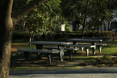 Empty stylish table with benches in park on sunny day