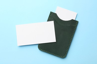 Leather business card holder with blank cards on light blue background, top view