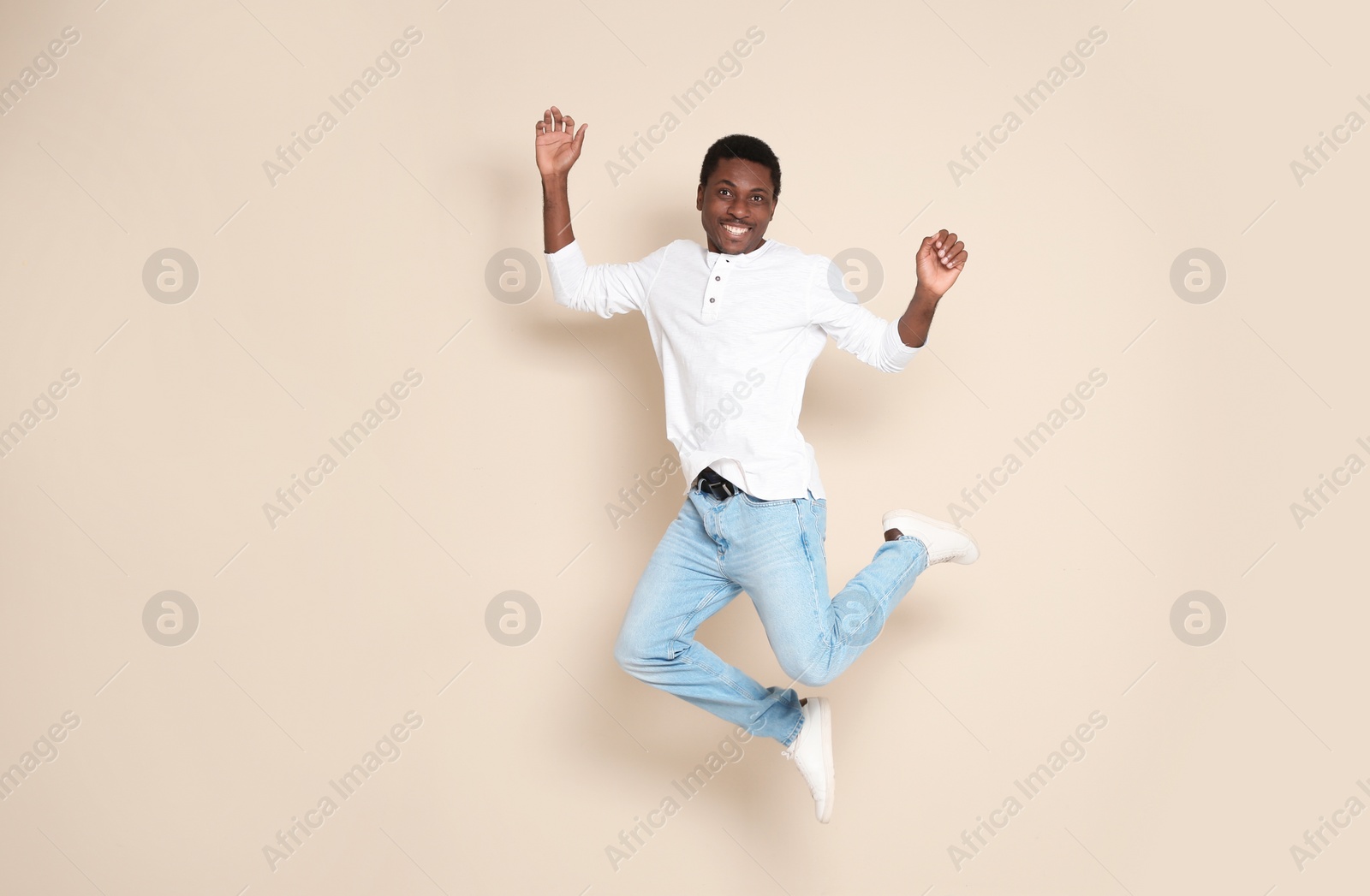 Photo of Full length portrait of African-American man jumping on color background
