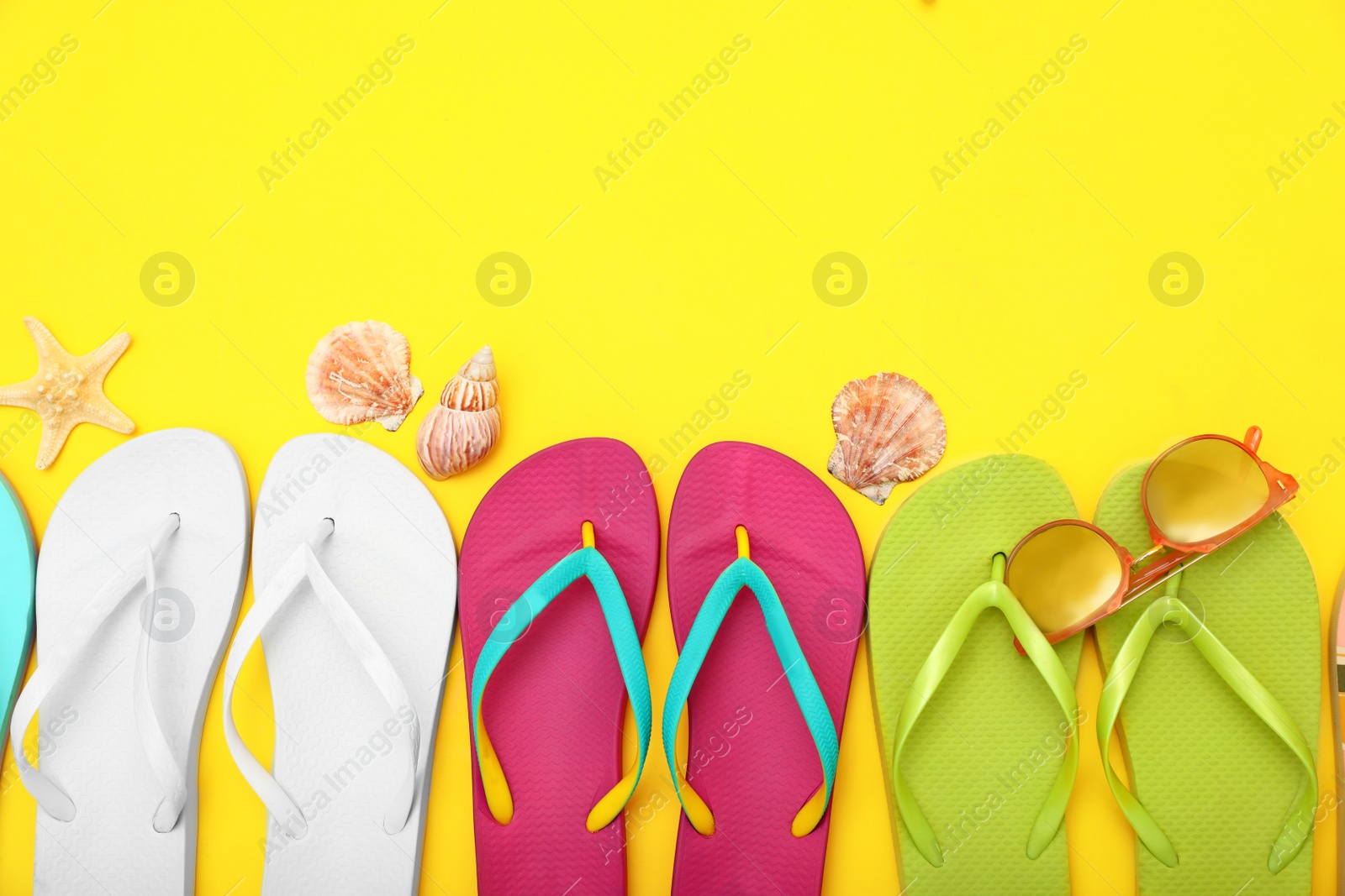 Photo of Flat lay composition with different flip flops on yellow background, space for text. Summer beach accessories