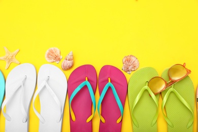 Photo of Flat lay composition with different flip flops on yellow background, space for text. Summer beach accessories