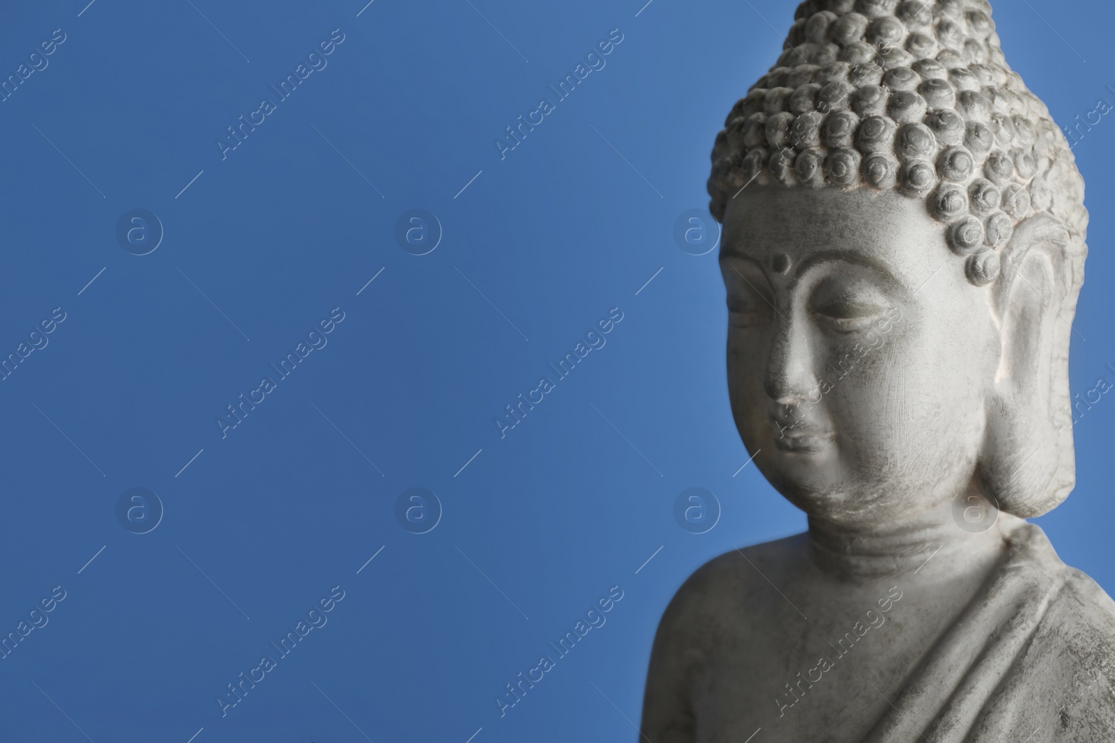 Photo of Beautiful stone Buddha sculpture on blue background. Space for text