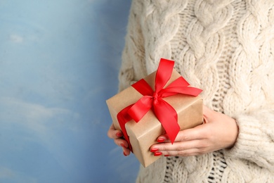 Photo of Young woman holding Christmas gift on blue background, closeup. Space for text