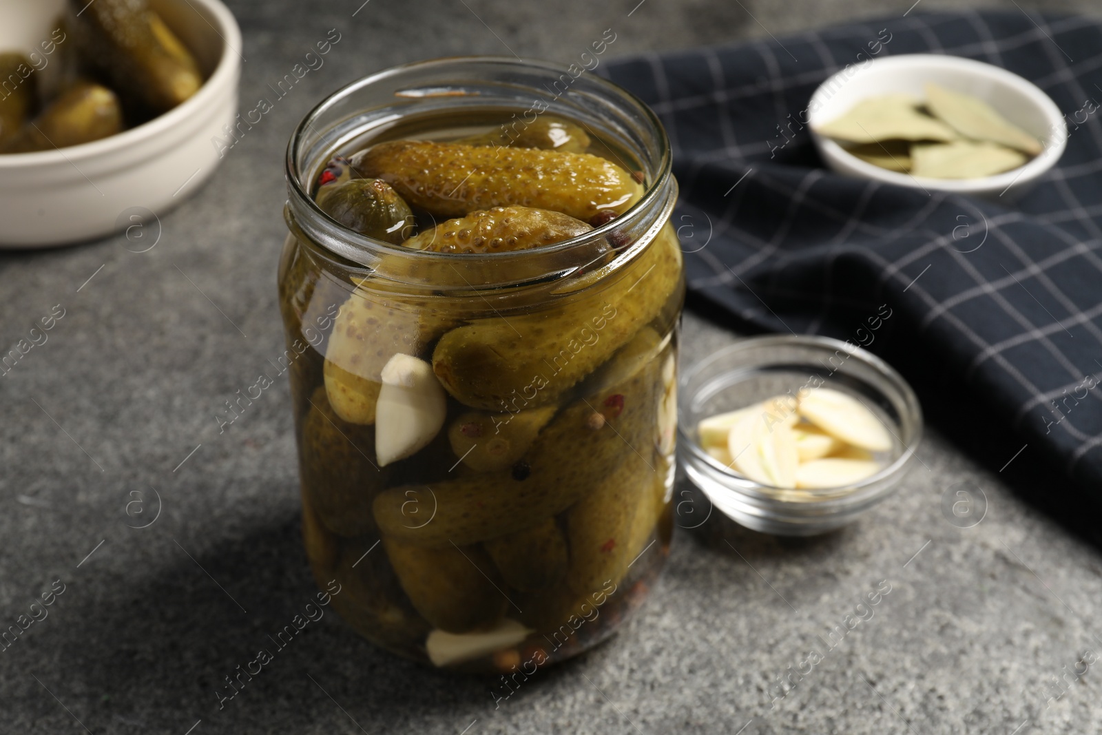 Photo of Tasty pickled cucumbers in glass jar on grey table, closeup