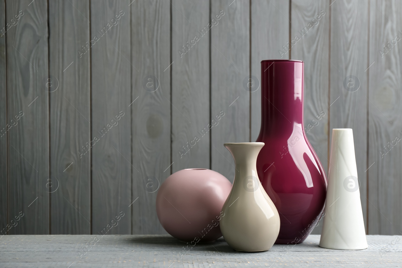 Photo of Stylish ceramic vases on grey wooden table. Space for text