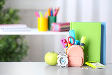 Alarm clock, apple and school stationery on white table. Space for text