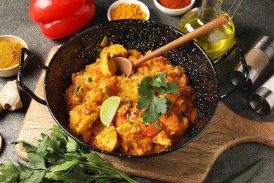 Photo of Delicious chicken curry and ingredients on grey table