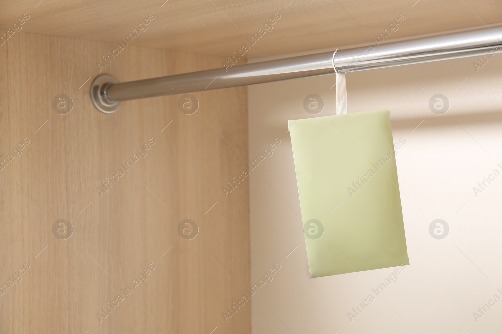 Photo of Scented sachet hanging on metal bar in wardrobe