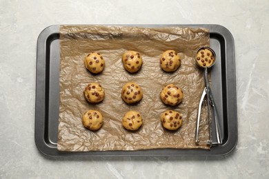 Tray with uncooked chocolate chip cookies on light grey table, top view