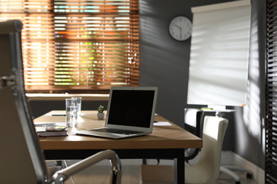 Laptop on wooden table in modern office