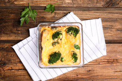 Photo of Tasty broccoli casserole in baking dish on wooden table, flat lay