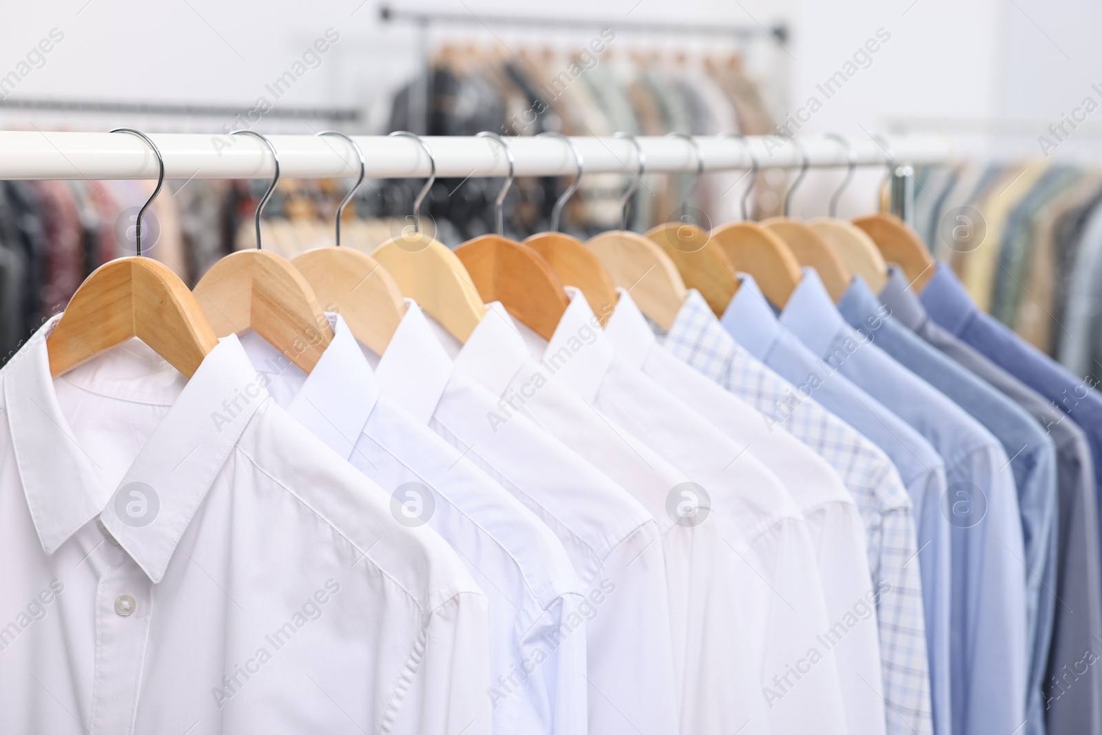 Photo of Dry-cleaning service. Many different clothes hanging on rack indoors, closeup