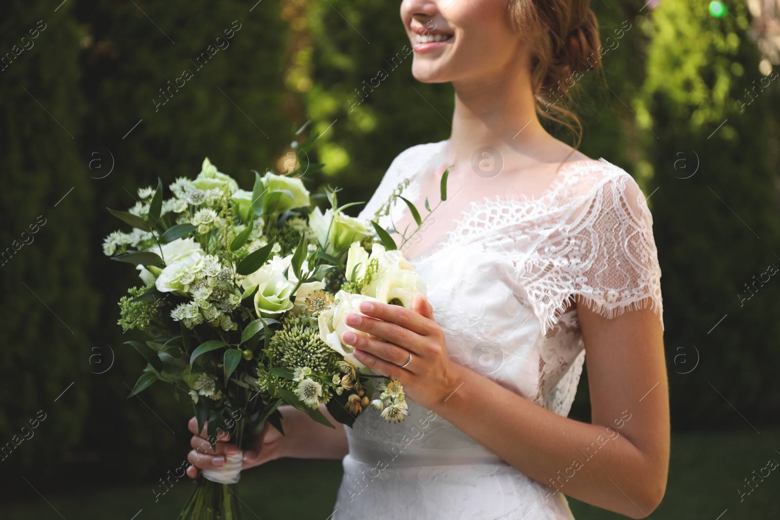 Photo of Bride in beautiful wedding dress with bouquet outdoors, closeup