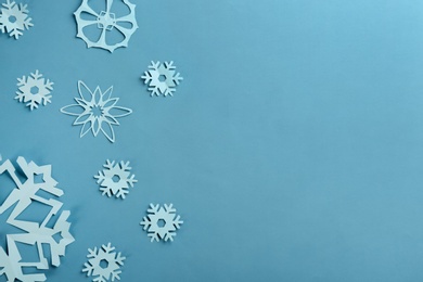 Photo of Many paper snowflakes on turquoise background, flat lay. Space for text