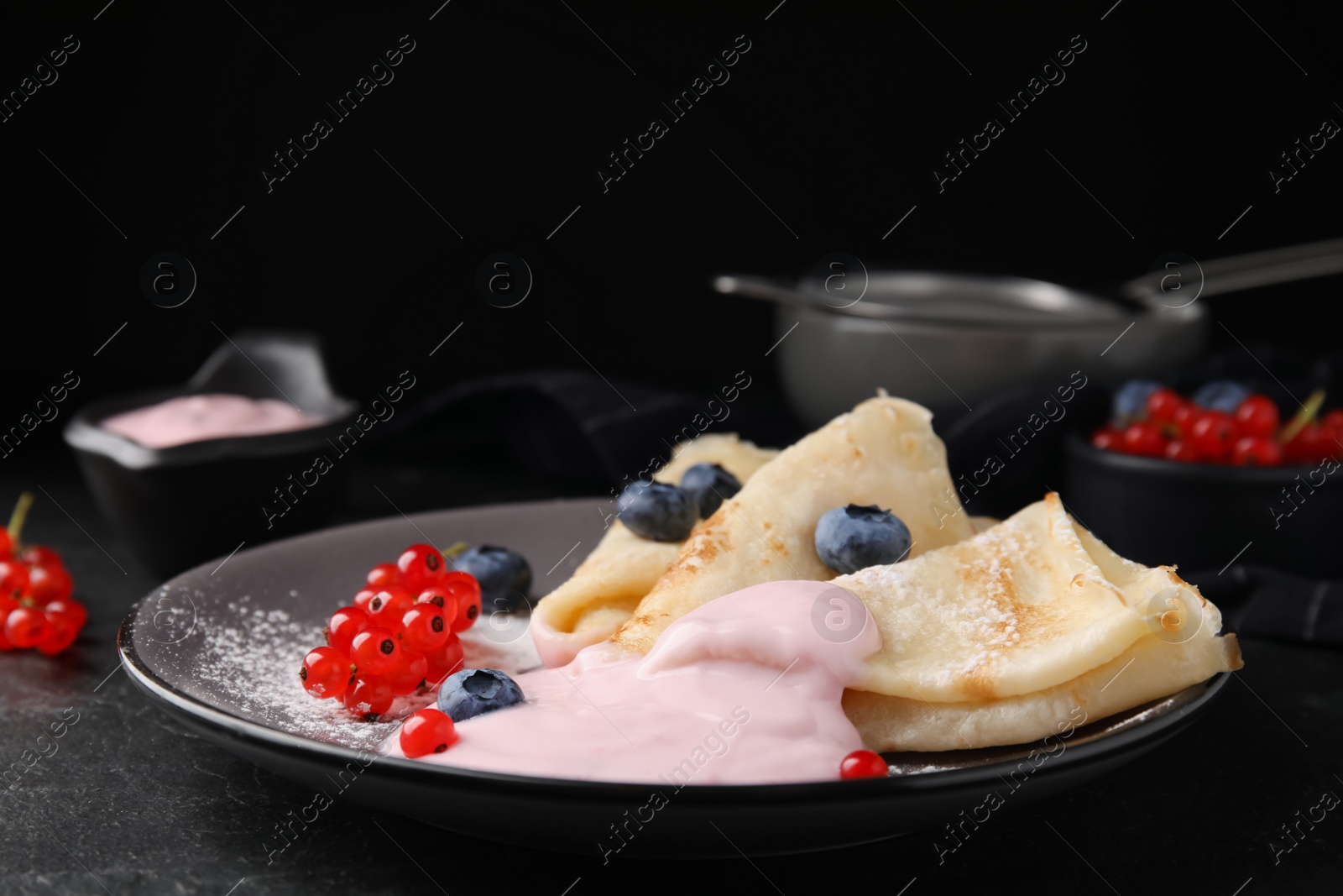 Photo of Delicious crepes with natural yogurt, blueberries and red currants on dark grey table. Space for text