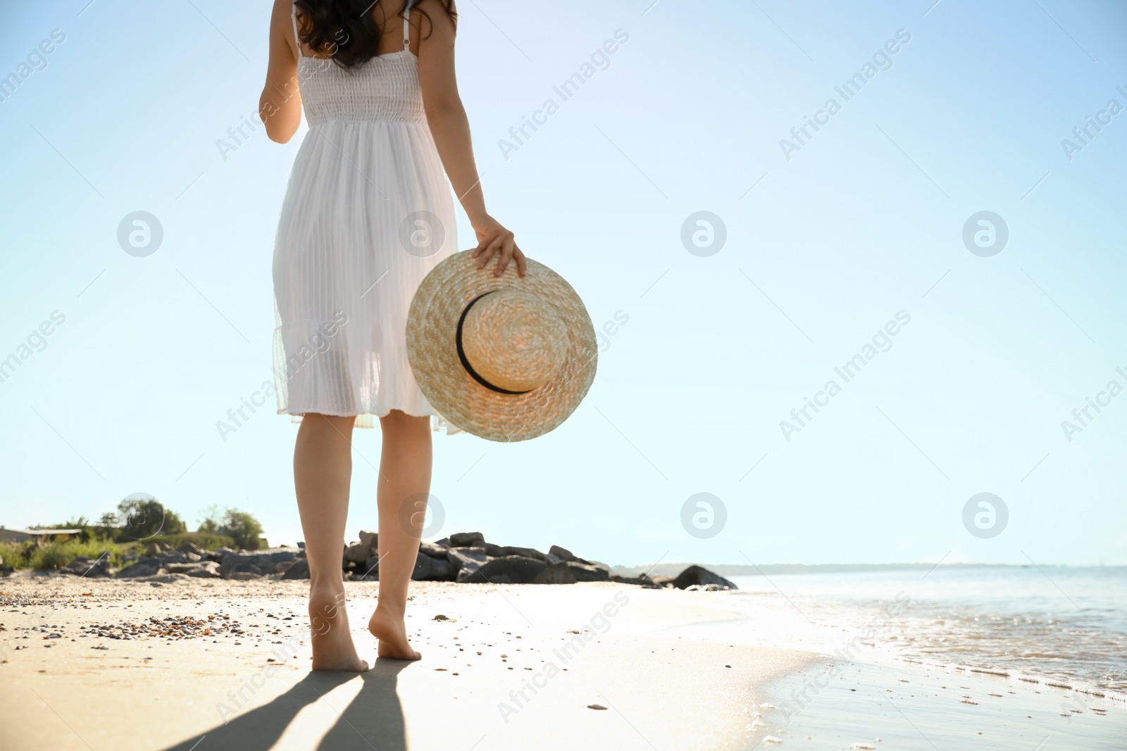 Photo of Young woman with hat walking on beach near sea, closeup. Space for text