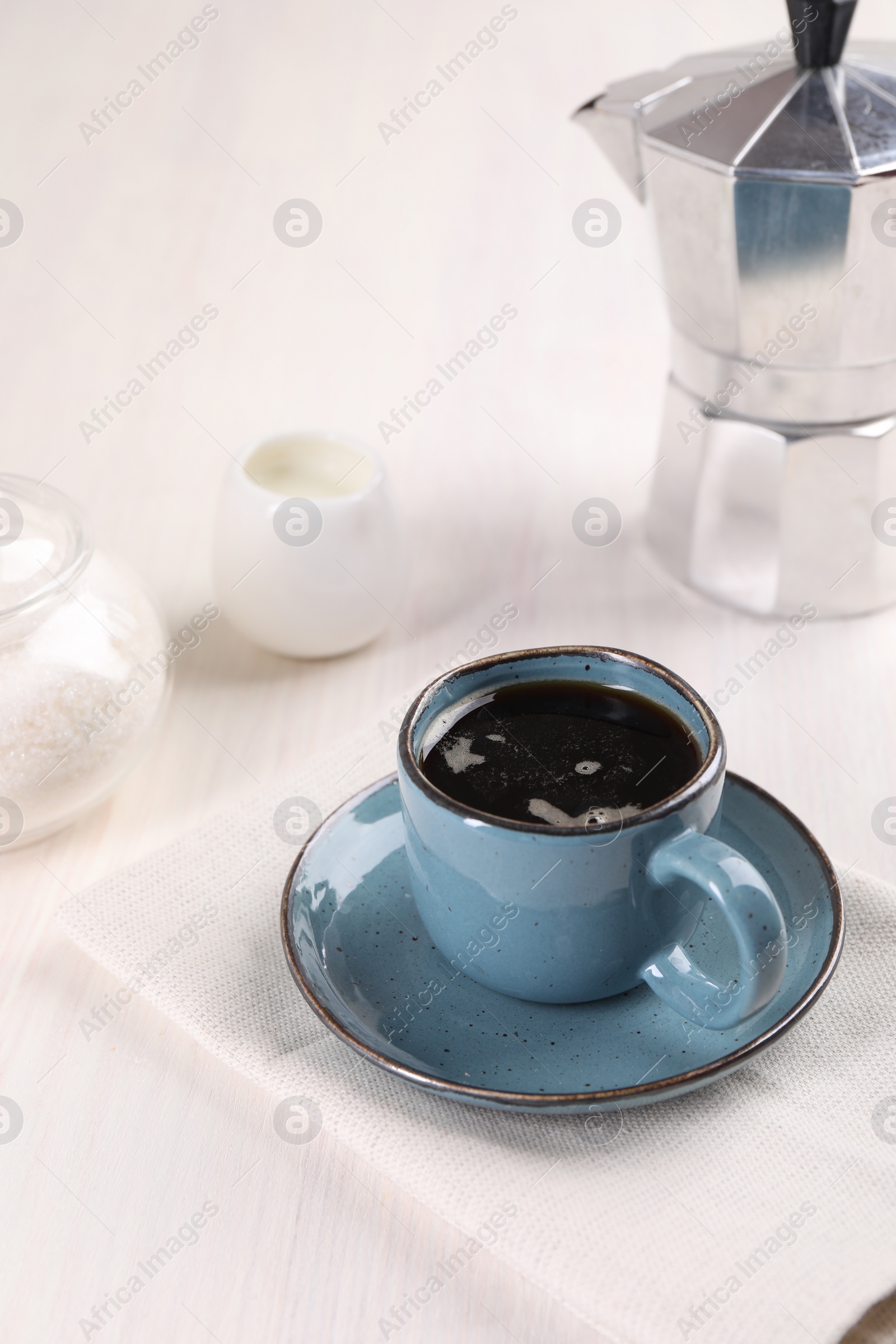 Photo of Delicious coffee in cup and moka pot on white wooden table