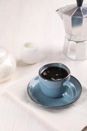 Photo of Delicious coffee in cup and moka pot on white wooden table