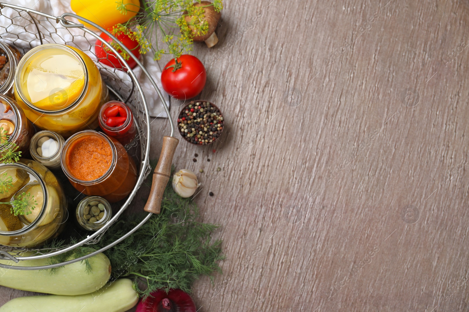 Photo of Flat lay composition with jars of pickled vegetables on brown table. Space for text