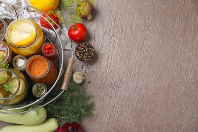 Flat lay composition with jars of pickled vegetables on brown table. Space for text