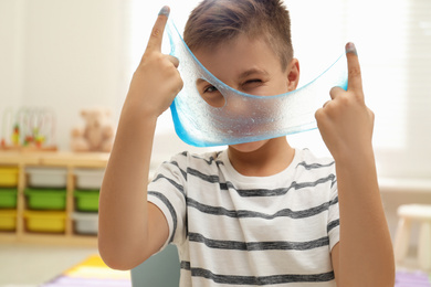 Photo of Little boy playing with slime in room