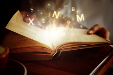 Woman reading shiny magic book with letters flying over it, closeup