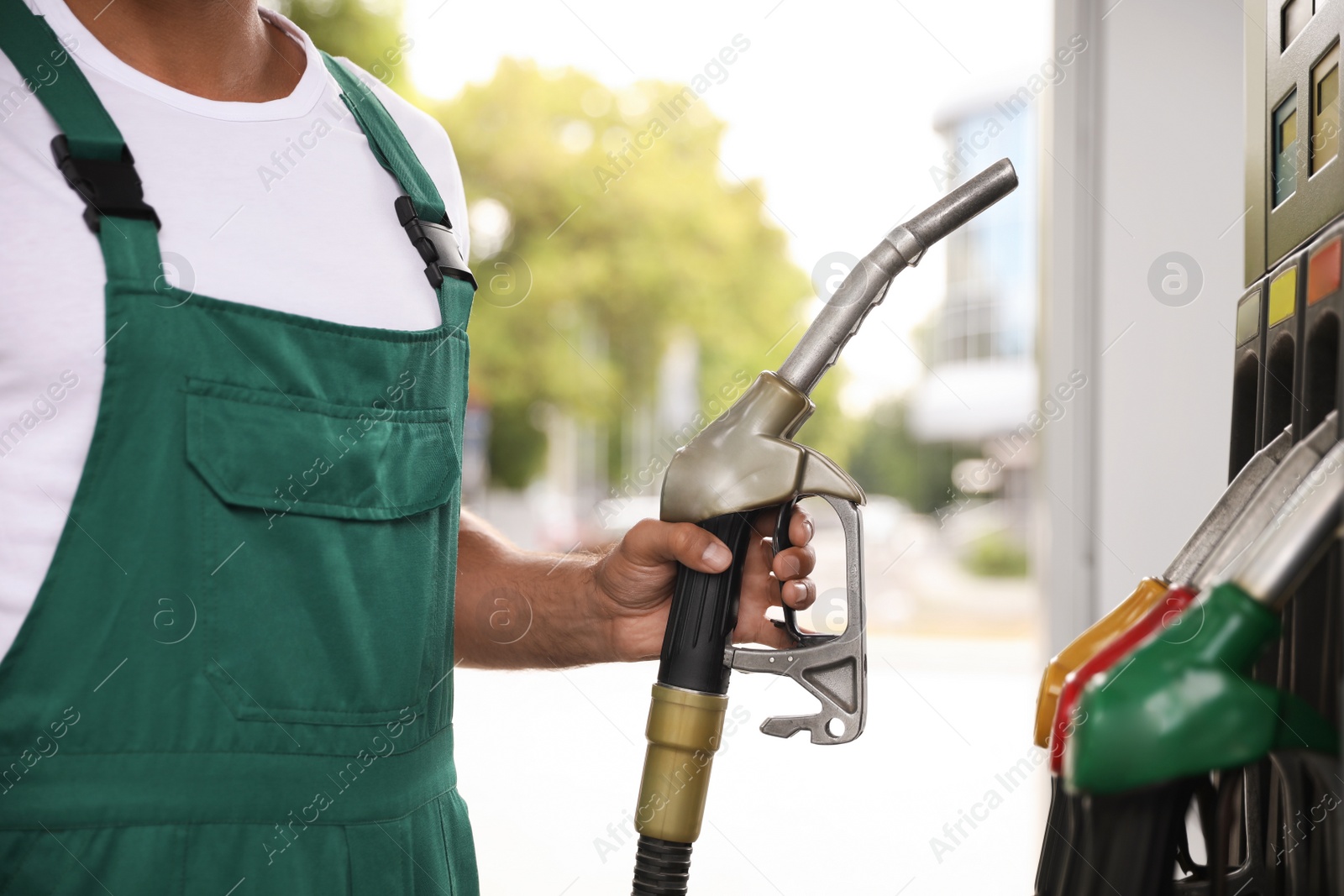 Photo of Worker taking fuel pump nozzle at modern gas station, closeup