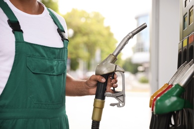 Photo of Worker taking fuel pump nozzle at modern gas station, closeup