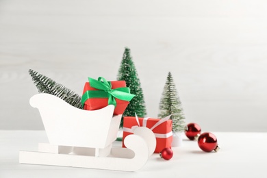 Photo of Beautiful Christmas composition with miniature sleigh on white table. Space for text