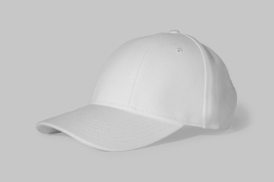 Stylish white baseball cap on light background