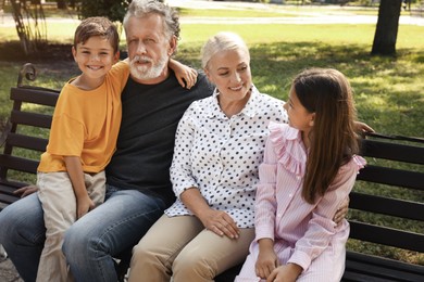 Happy grandparents with little children resting together in park