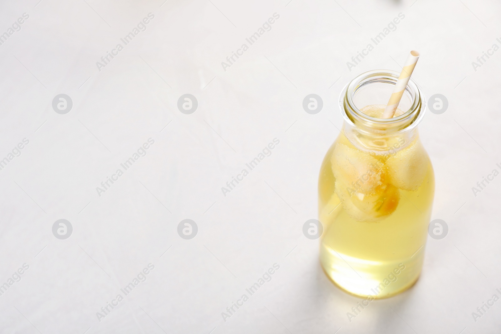 Photo of Bottle with tasty melon ball drink on light table. Space for text