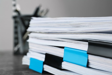 Photo of Stack of documents with binder clips on grey stone table, closeup view