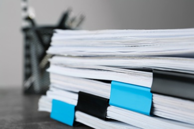 Stack of documents with binder clips on grey stone table, closeup view