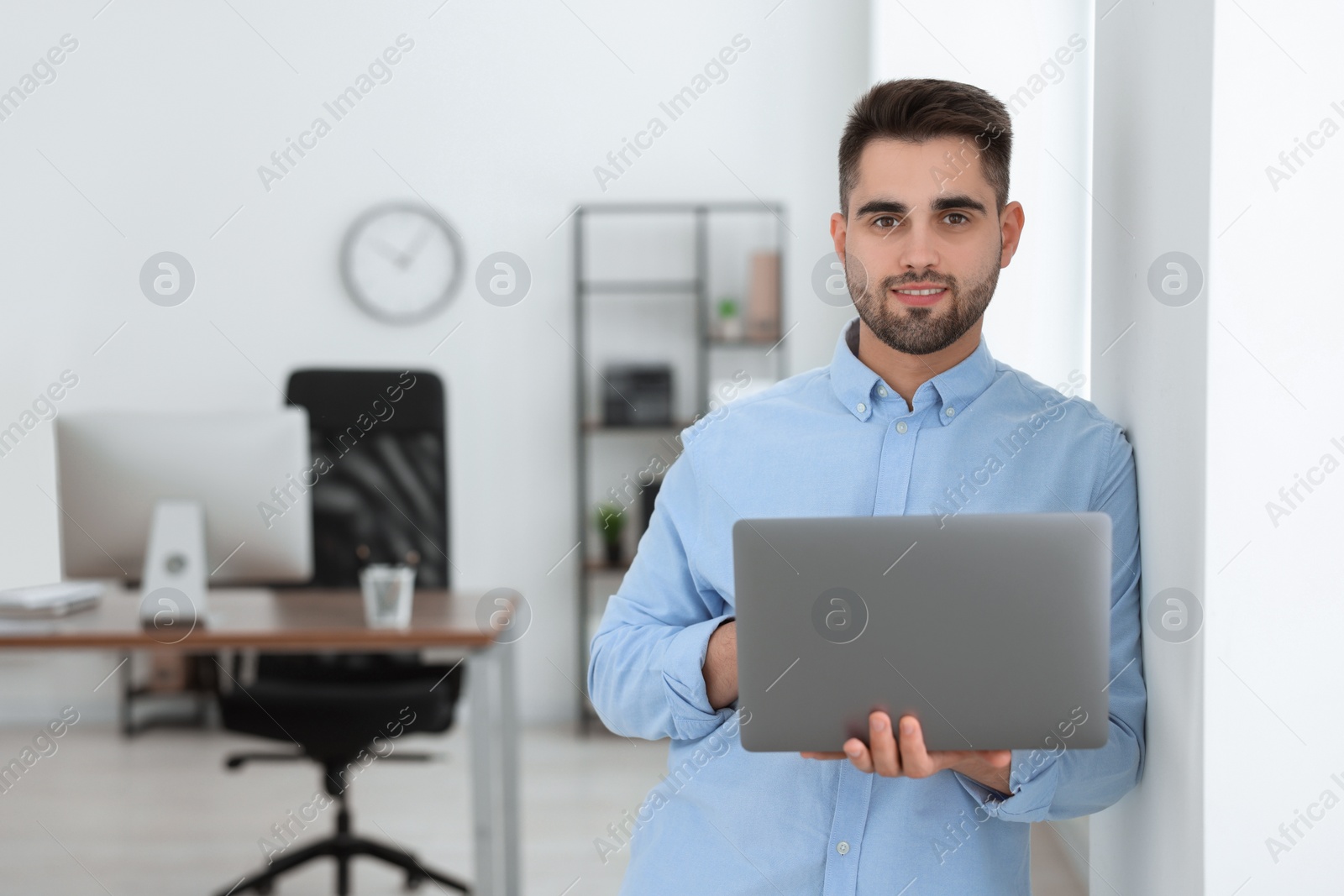 Photo of Happy young programmer with laptop in office