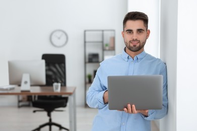 Photo of Happy young programmer with laptop in office