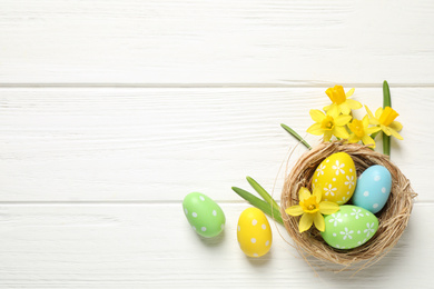 Photo of Flat lay composition with Easter eggs on white wooden background. Space for text