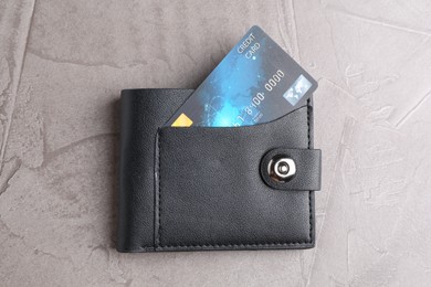 Photo of Credit card in leather wallet on grey textured table, top view